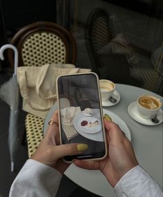 a woman holding up her cell phone to take a photo of food on the table