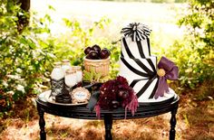 a table topped with a black and white striped cake next to other items on top of it