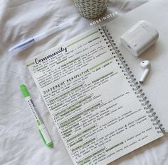 a notepad and pen sitting on top of a white sheet next to a cup