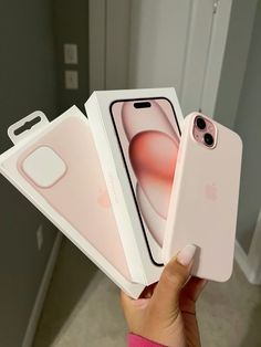 someone holding two iphones in their hands, one is pink and the other is white