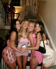 four beautiful young women standing next to each other in front of a staircase with their arms around one another