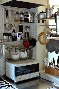 a microwave oven sitting on top of a counter next to a shelf filled with pots and pans