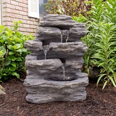 a water fountain made out of rocks in front of a house