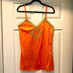 Brand New With Tag! Orange Silk Camisole With Gold Lace Trim! -88% Silk -12% Spandex -Perfect Condition! Never Worn! -Adjustable Straps -Length As Shown 31.5” (Can Go Longer Or Shorter) -17” Bust Orange Stretch Tank Top, Orange Camisole Tank Top For Spring, Fitted Orange Camisole For Summer, Orange Sleeveless Camisole For Spring, Orange Stretch Tank Top For Party, Stretch Orange Tank Top For Party, Orange Sleeveless Tops For Party, Sleeveless Orange Party Tops, Orange Stretch Top With Built-in Bra