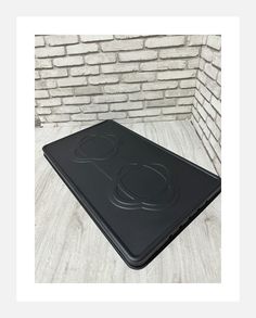 a black stove top sitting on top of a wooden floor next to a brick wall