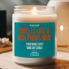 a candle that reads smells like a dolphins win your name lucky game day candle on a table