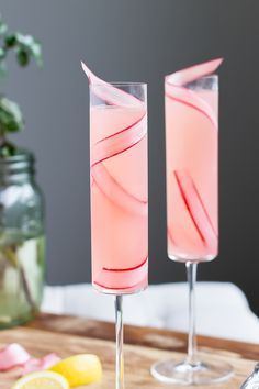 two glasses filled with pink liquid sitting on top of a table next to each other