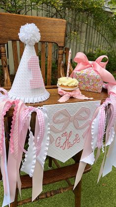 a table with pink and white decorations on it, including a cake and cupcake