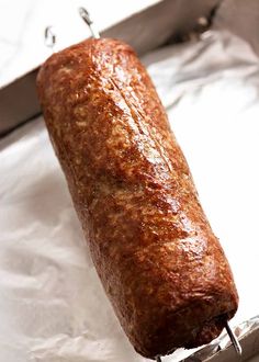 a meatloaf is being cooked in a pan with tongs on the side