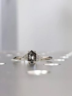 an engagement ring with a black diamond surrounded by smaller white diamonds on a countertop