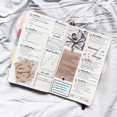 an open notebook with writing on it sitting on top of a white sheet covered bed