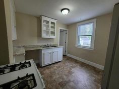 an empty kitchen with white cabinets and wood flooring is pictured in this image from the doorway to the living room