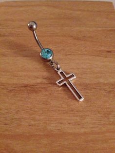 a cross with a blue stone hanging from it's side on a wooden surface