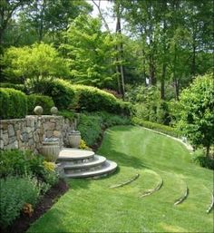 an outdoor garden with steps leading up to the lawn and trees in the back ground