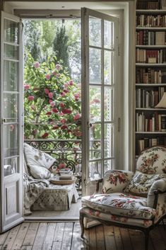 an open door leading to a sitting area with flowers on the window sill and bookshelves