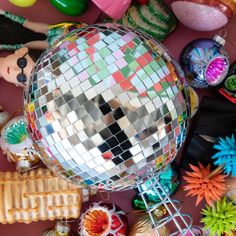 a disco ball surrounded by other toys on a pink surface with lots of different colors and shapes