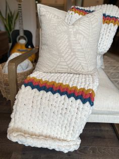 a white crocheted blanket sitting on top of a chair next to a pillow