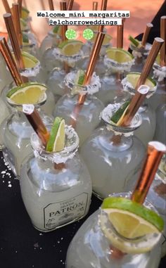 there are many glasses filled with drinks and garnished with limes on the table