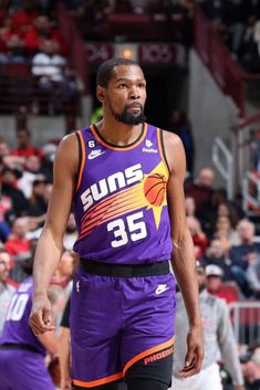 a basketball player in purple uniform standing on the court