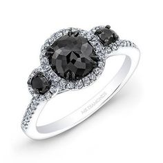 an engagement ring with three black and white diamonds on the band, set in 18k white gold