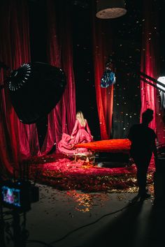 a woman sitting on top of a red couch in front of a tv set with lights