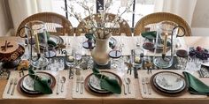 the table is set with dishes, silverware and green napkins for an elegant dinner