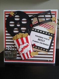 a birthday card with popcorn, film reel and movie claps on it's side