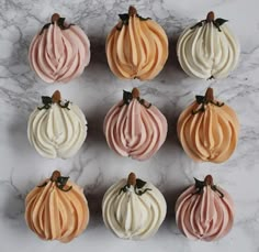 six cupcakes with frosting in different colors on a marble countertop top