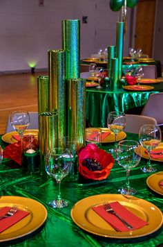 the table is set with green and yellow plates, silverware, and red napkins