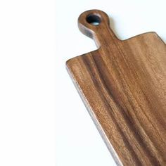 a wooden cutting board sitting on top of a white table next to a black object