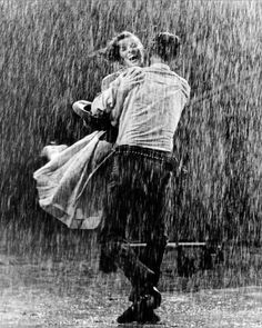 black and white photograph of two people in the rain, one holding the other's back