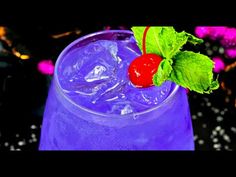 a blue drink with a cherry on the top and green leafy garnish