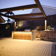 an outdoor kitchen is lit up at night with lights on the counter and brick flooring