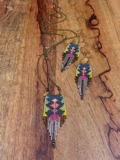 three pieces of jewelry sitting on top of a wooden table next to a necklace and earring