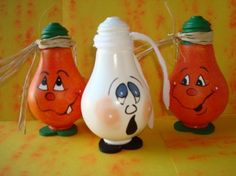 three orange and white vases with faces painted on them, one has a green cap