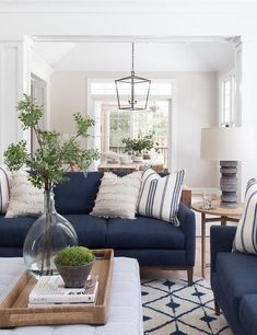 a living room filled with blue couches and white pillows on top of a rug