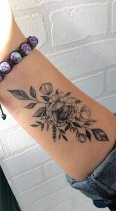 a woman's arm with a flower tattoo on the left side of her arm