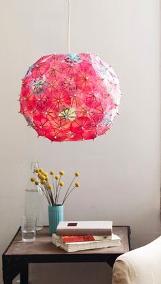 a pink umbrella hanging from the ceiling above a table with books and vases on it