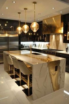 a modern kitchen with marble counter tops and gold pendant lights hanging from the ceiling over the island