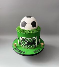 a soccer themed cake with green frosting and grass on the top, topped with a soccer ball