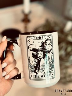 a woman holding a coffee mug with a witch on it's front and side