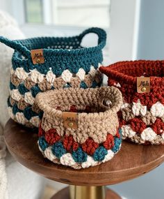 three crocheted baskets sitting on top of a wooden table next to each other