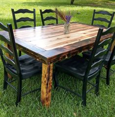 a wooden table and chairs sitting in the grass with vases on top of them