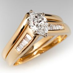 two gold wedding rings with an oval diamond and baguettes