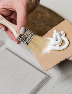 a person is using a paint brush on a piece of wood