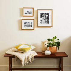 three framed pictures hang on the wall next to a table with a potted plant