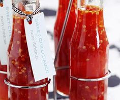 several bottles filled with red sauce sitting on top of a table