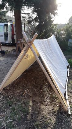 a large white tarp sitting on top of a dirt field next to a tree