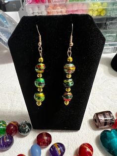 Green and gold  glazed bead earrings with wire hook assembly with gold resin dividers. Glazed in mainly green and gold but with a touch of red and black glaze. Perfect for any occasions. One of a kind Multicolor Festive Jewelry With Ear Wire, Festive Multicolor Jewelry With Ear Wire, Gold Beaded Earrings With French Hook As Gift, Green Adjustable Earrings With French Hook, Green Earrings With French Hook And Adjustable Fit, Gold Drop Earrings With Colorful Beads, Gold Earrings With Colorful Beads For Party, Green Czech Glass Earrings With Colorful Beads, Green Earrings With Colorful Beads For Gifts