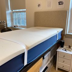 a bed with a blue mattress sitting on top of it next to a white dresser